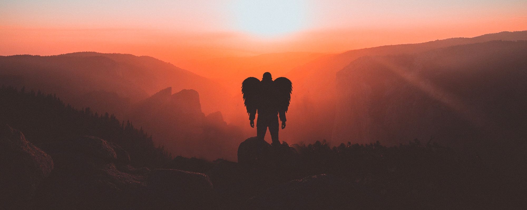 Angel silhouette on top of a cliff, at sunset