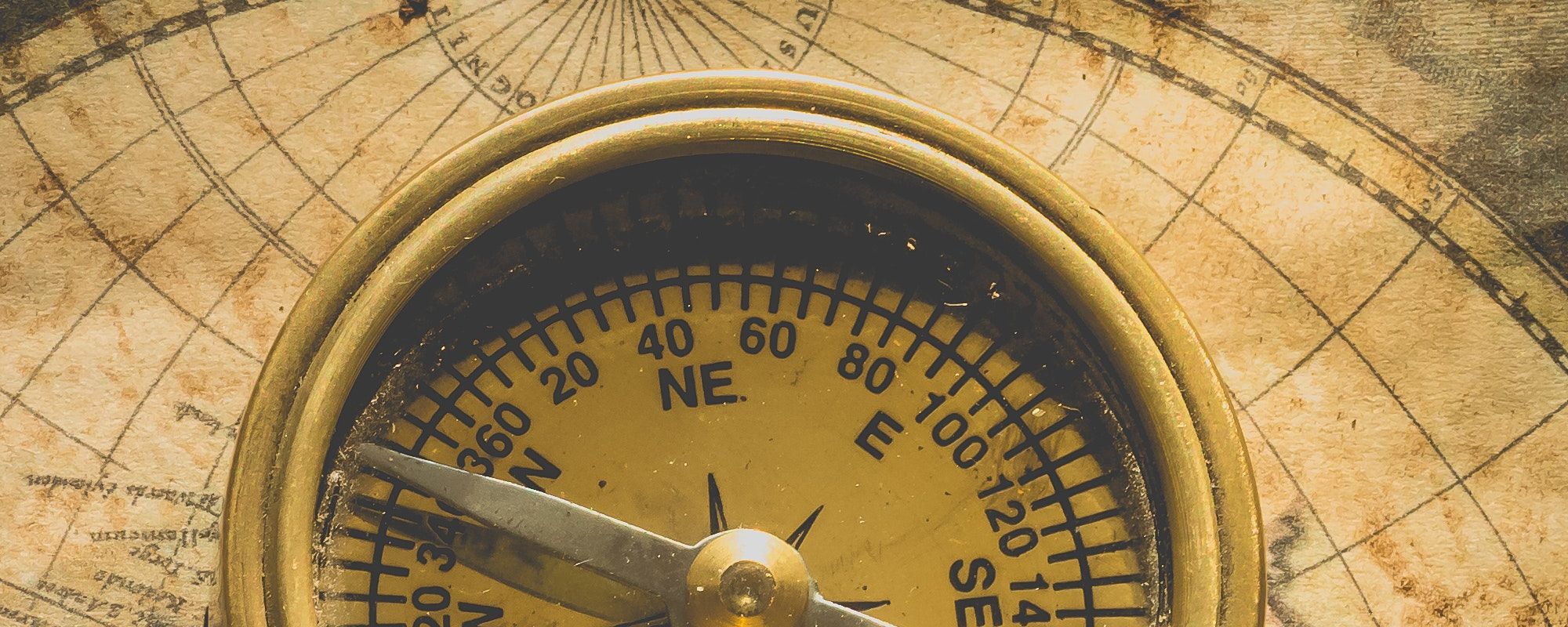 Detail of an antique compass placed on a map